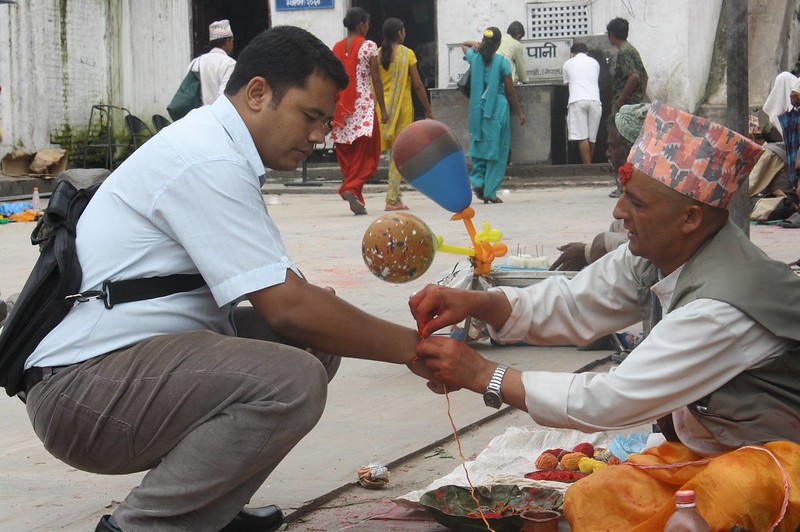 Man tying rakshya thread from pandit